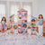 Two girls playing with a five-foot-tall wooden dollhouse featuring 16 play spaces and pink multi-floor interior